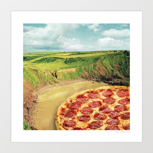 Coastal Pizza Bay surreal art print — a large golden pepperoni pizza sitting at landscape scale in a dramatic coastal bay with green clifftops rocky headlands and a sweeping sandy cove below a cloudy blue sky, food and coastal surrealism wall art for kitchens beach houses pizzerias and seaside cafe interiors
