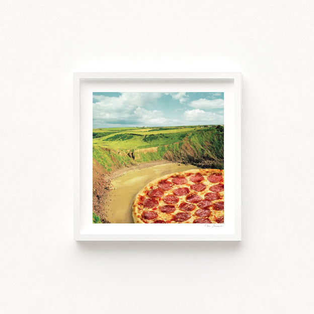 Coastal Pizza Bay art print second view — surreal collage of a perfectly topped pepperoni pizza integrated into a clifftop coastal landscape with rolling green headlands and sandy shore, quirky food art for beach house decor holiday homes seaside restaurants and pizza lover gift ideas